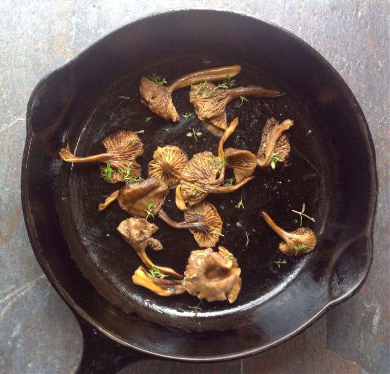 cooked yellowfoot chanterelles with thyme in a cast iron skillet