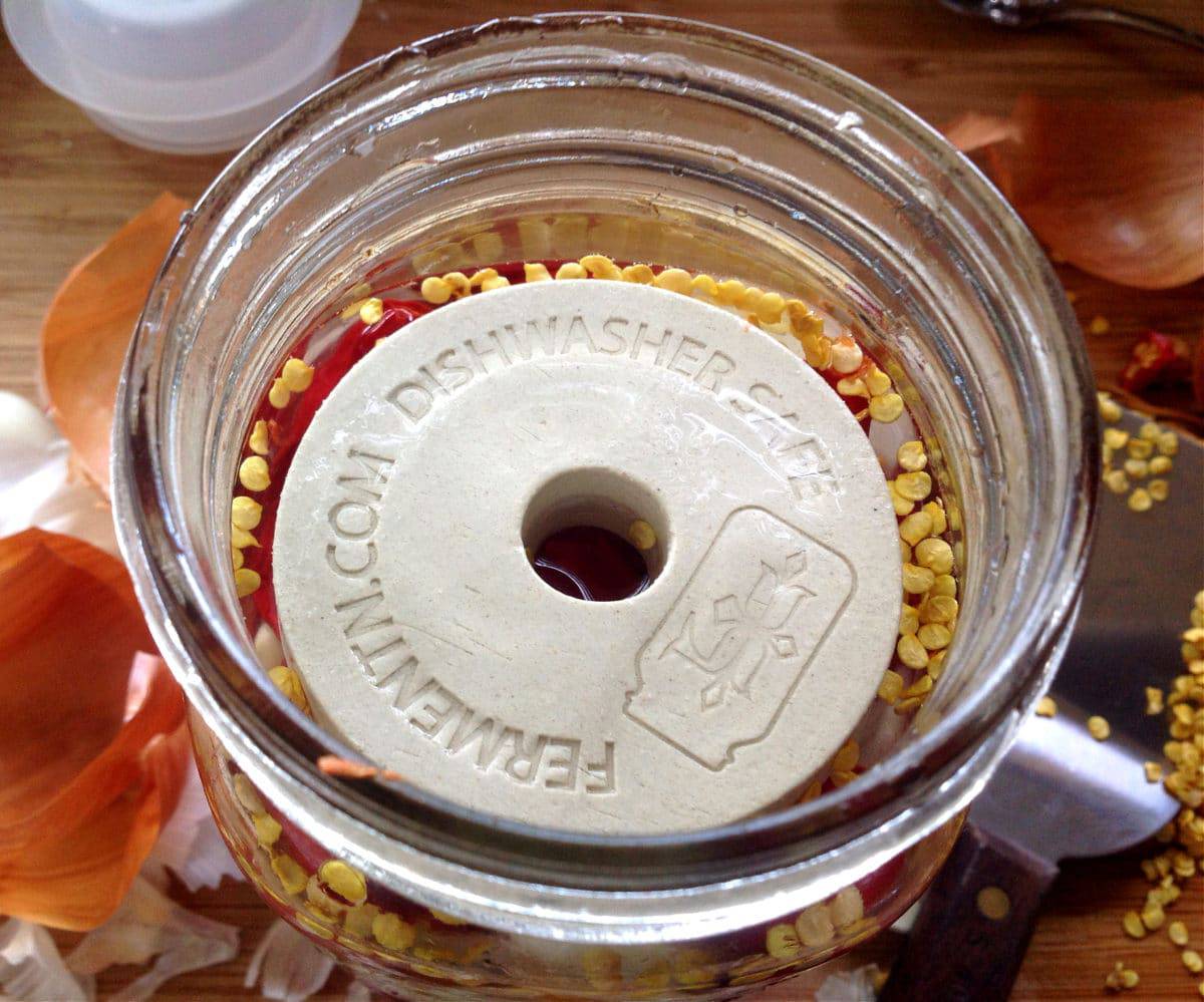 a fermentation weight on top of the peppers in a jar