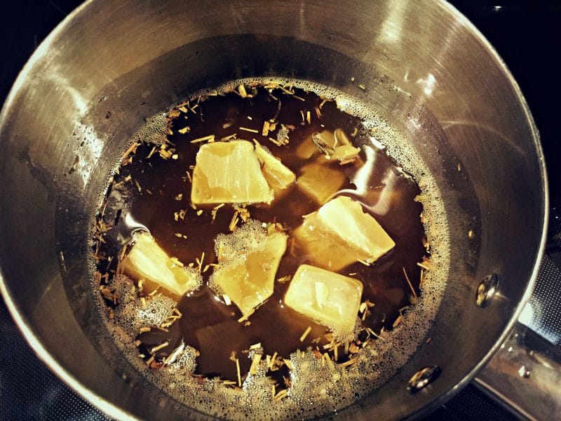 beeswax chunks in the oil and herbs mixture in a pot