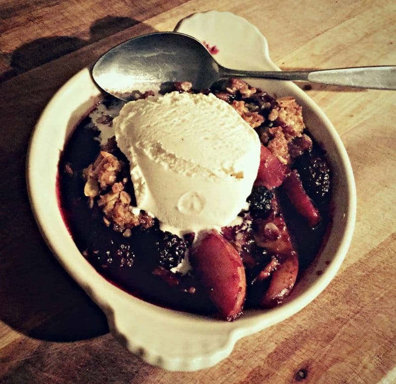 a dish of pear and blackberry crisp with a scoop of ice cream