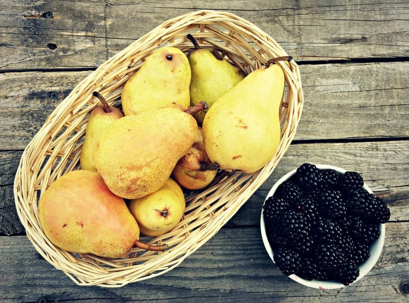 a basket of pears and a bowl of blackberries