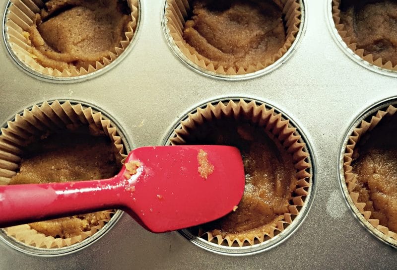 pressing pumpkin coconut mixture into muffin cups with a spatula