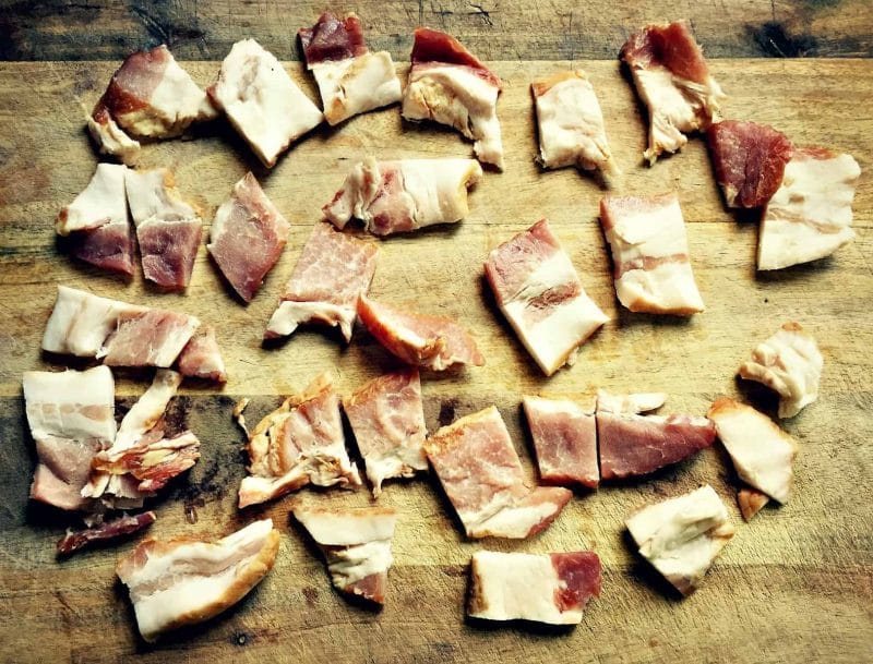 chunks of raw bacon on a wooden cutting board