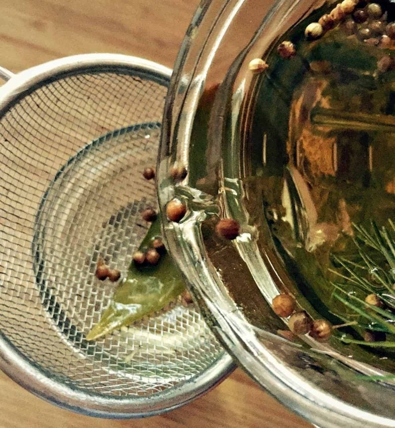 straining infused gin through a mesh sieve
