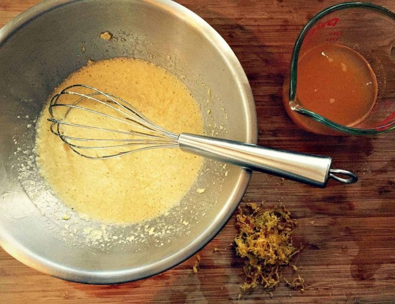 a metal bowl with the butter, sugar, and eggs mixture and a whisk