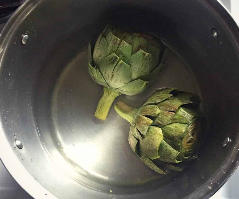 trimmed artichokes in a pot of water