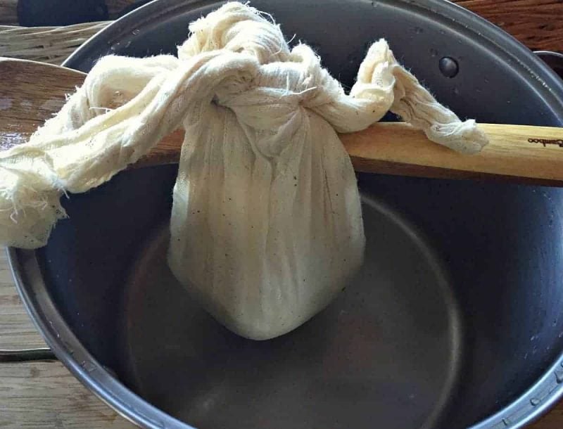 hanging the cheese curds over a pot to drain