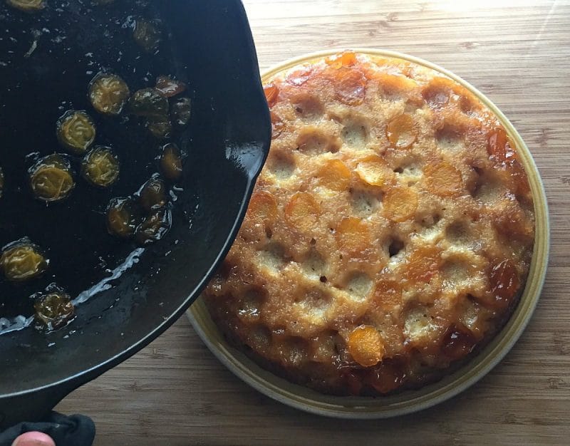 turning plum cake out of skillet onto a plate