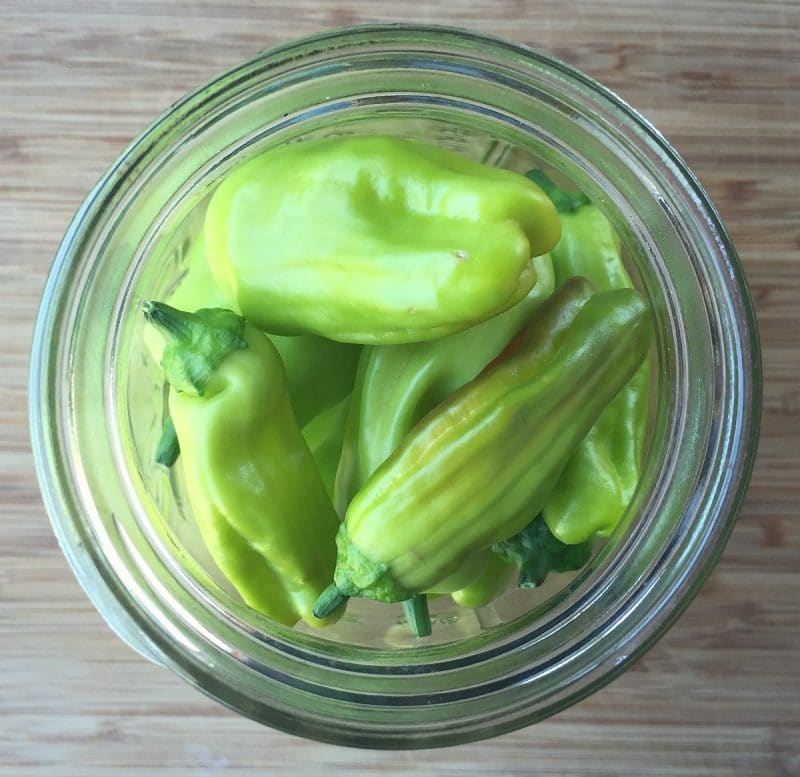 top down view of a jar full of fresh pepperoncini peppers