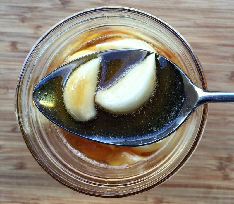 fermented garlic cloves in honey on a spoon