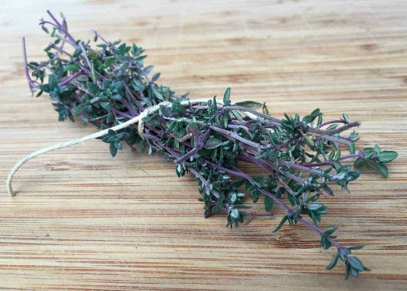 a bundle of thyme on a wooden cutting board