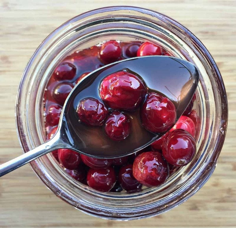 a spoon with fermented cranberries in honey