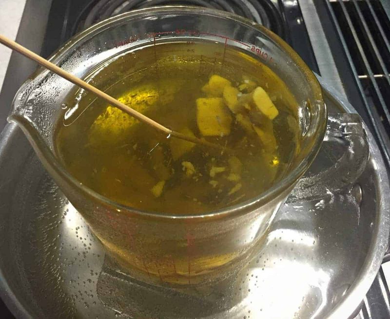 beeswax melting in a glass measuring cup of oil