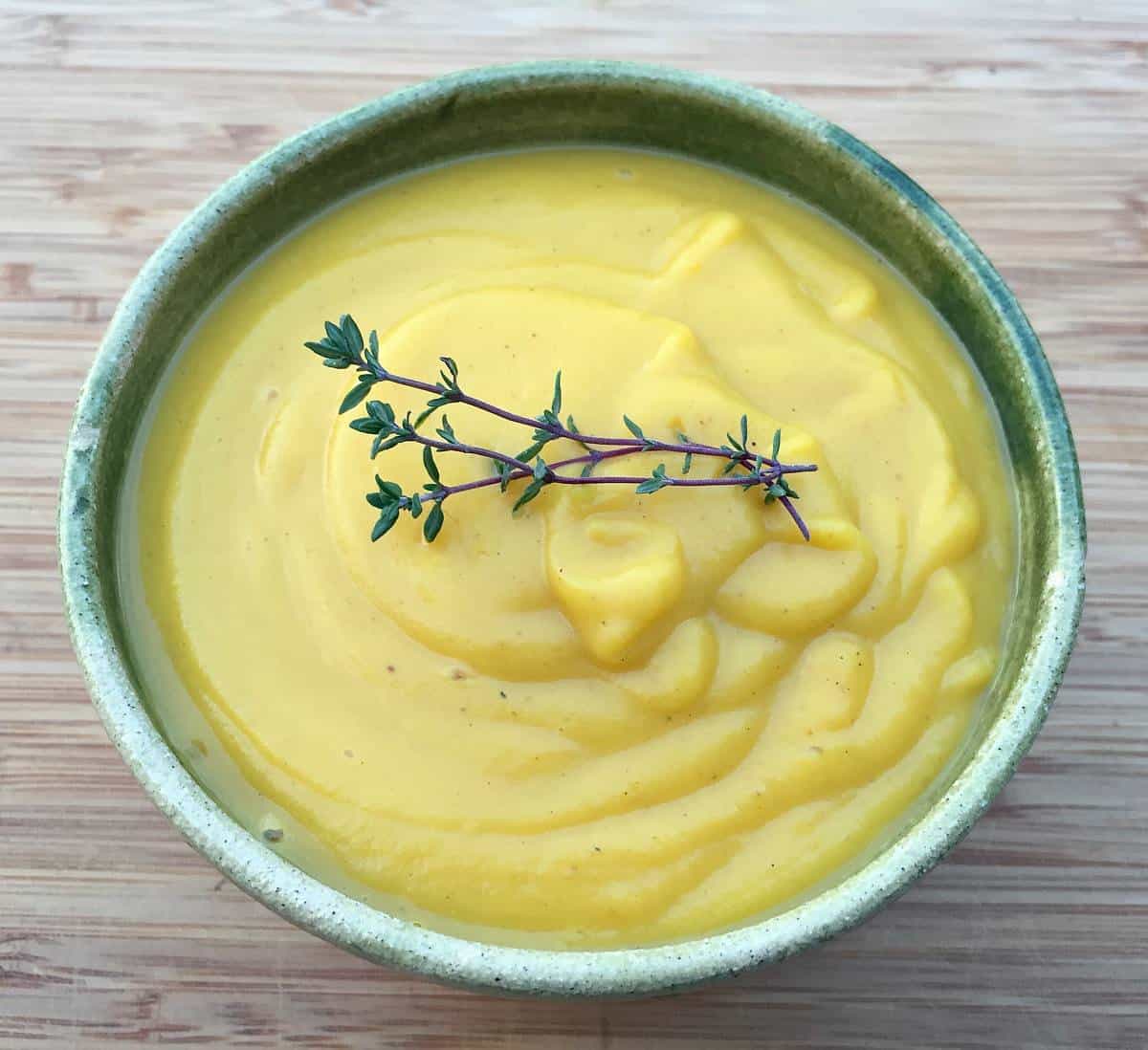 A bowl of pumpkin coconut soup with fresh thyme.