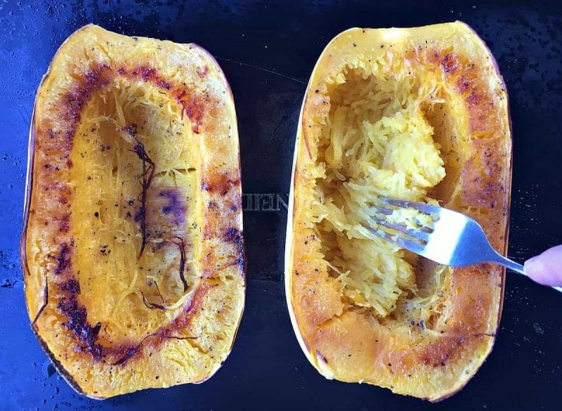 Scooping out spaghetti squash strands with a fork for winter squash recipes.