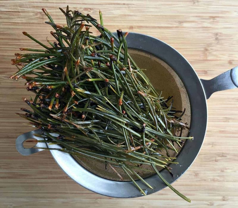 straining the pine and rosemary out of the oil