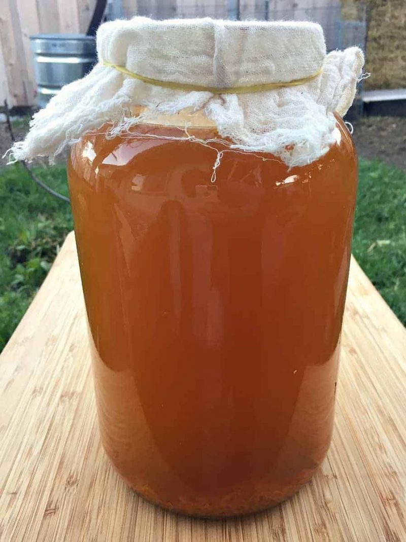 a one gallon wide mouth jar of turmeric soda covered with cheesecloth