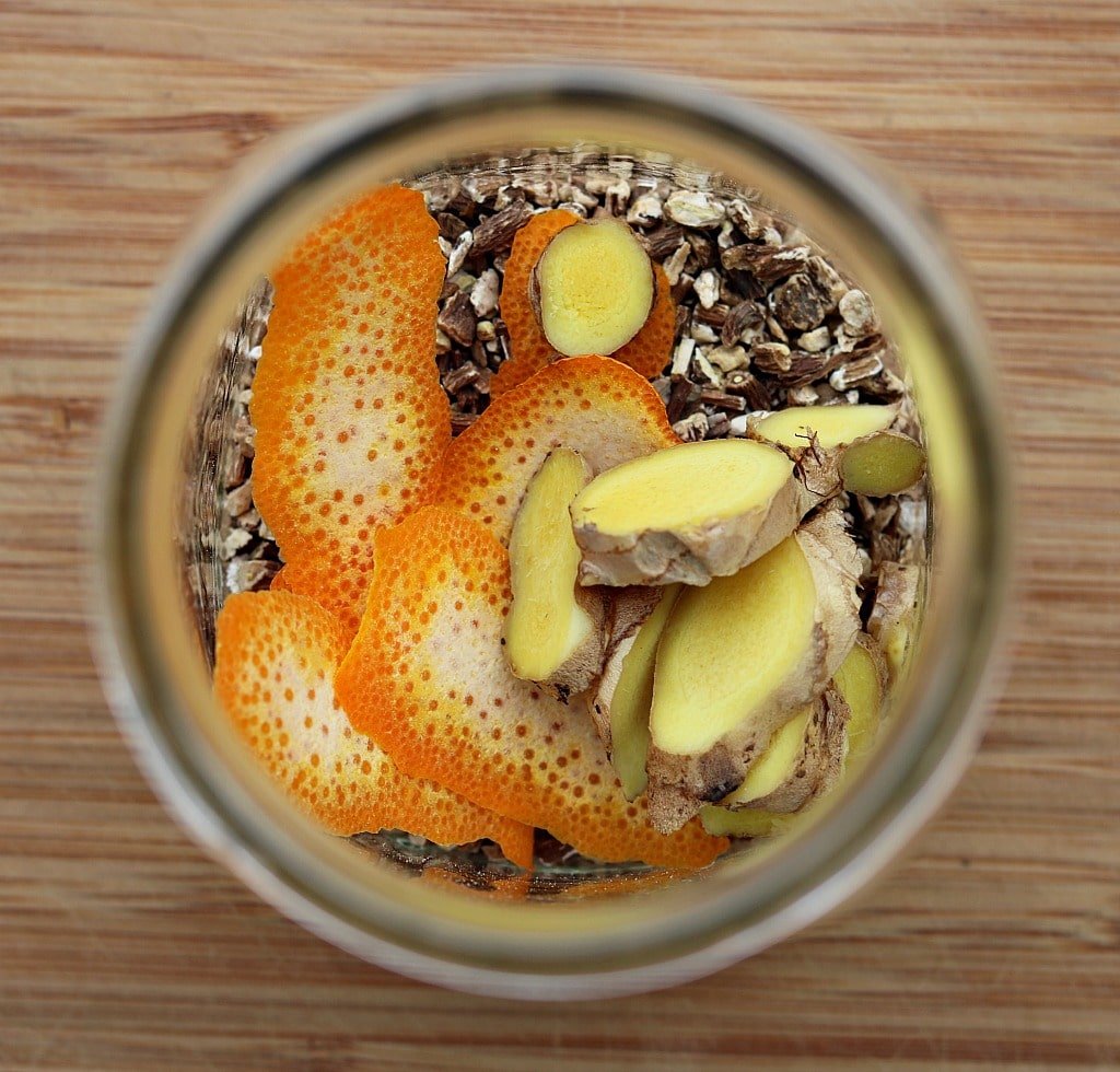 Looking into a mason jar filled with dandelion roots, ginger, and orange peel