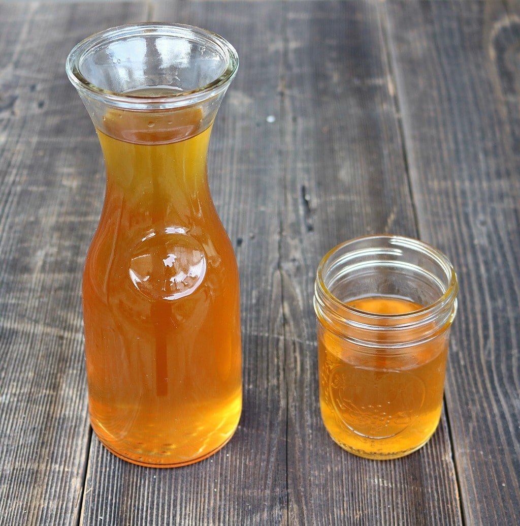 Glass decanter of dandelion root bitters next to mason jar of bitters