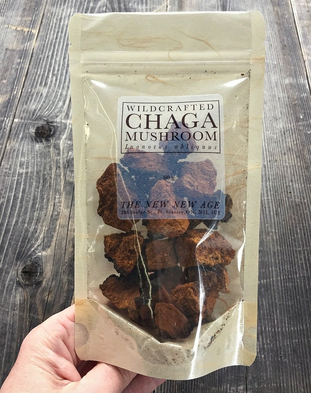 a hand holding a bag of wildcrafted chaga from the new new age