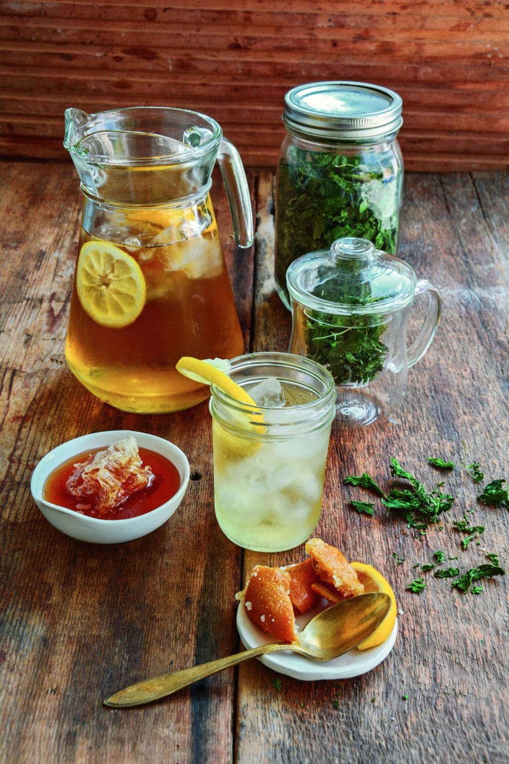 a pitcher of stinging nettle infusion with nettle ade ingredients on a wooden table