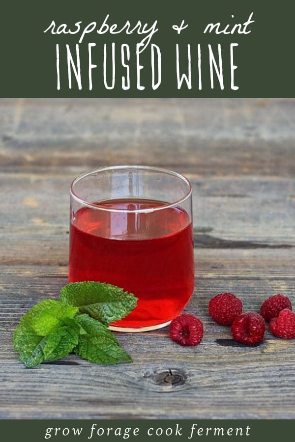 A glass of raspberry mint infused wine on a wood table.