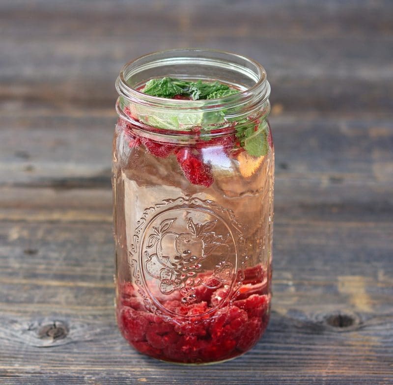 rasperries and mint infusing in a quart jar of wine