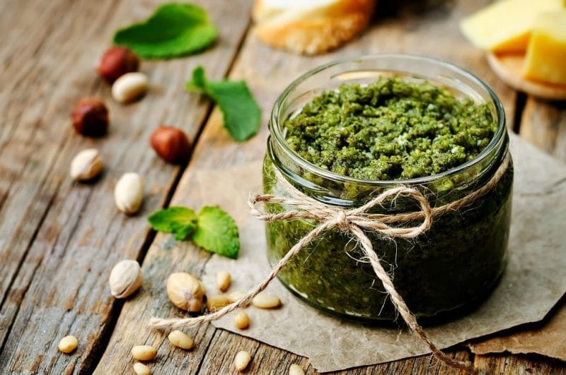 Basil is a common herb that is most often used in the kitchen, but it is also good for the garden and has amazing health benefits! Learn about 10 reasons to grow basil and the benefits of basil. a jar of basil pesto