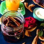 Reishi infused red wine in a jar garnished with a piece of mushroom, surrounded by a ingredients, with a dark background and vibe.