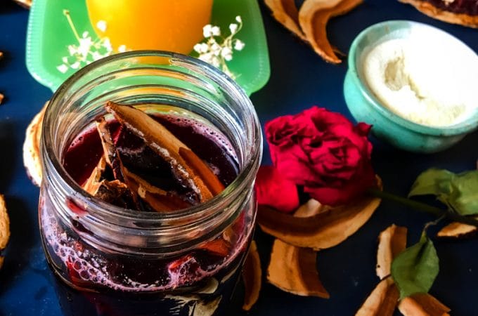 Reishi infused red wine in a jar garnished with a piece of mushroom, surrounded by a ingredients, with a dark background and vibe.