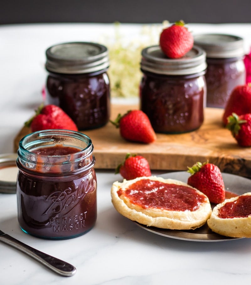 an open jar of strawberry honey butter and an english muffin