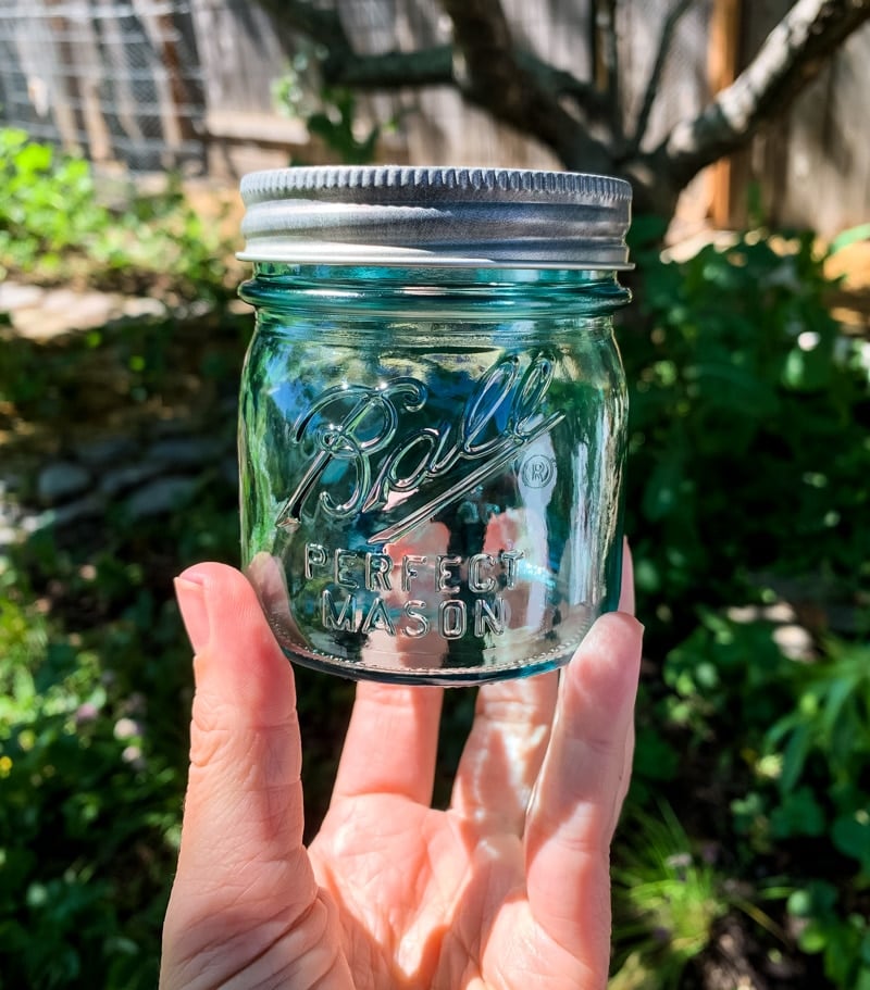 a hand holding an aqua vintage ball jar