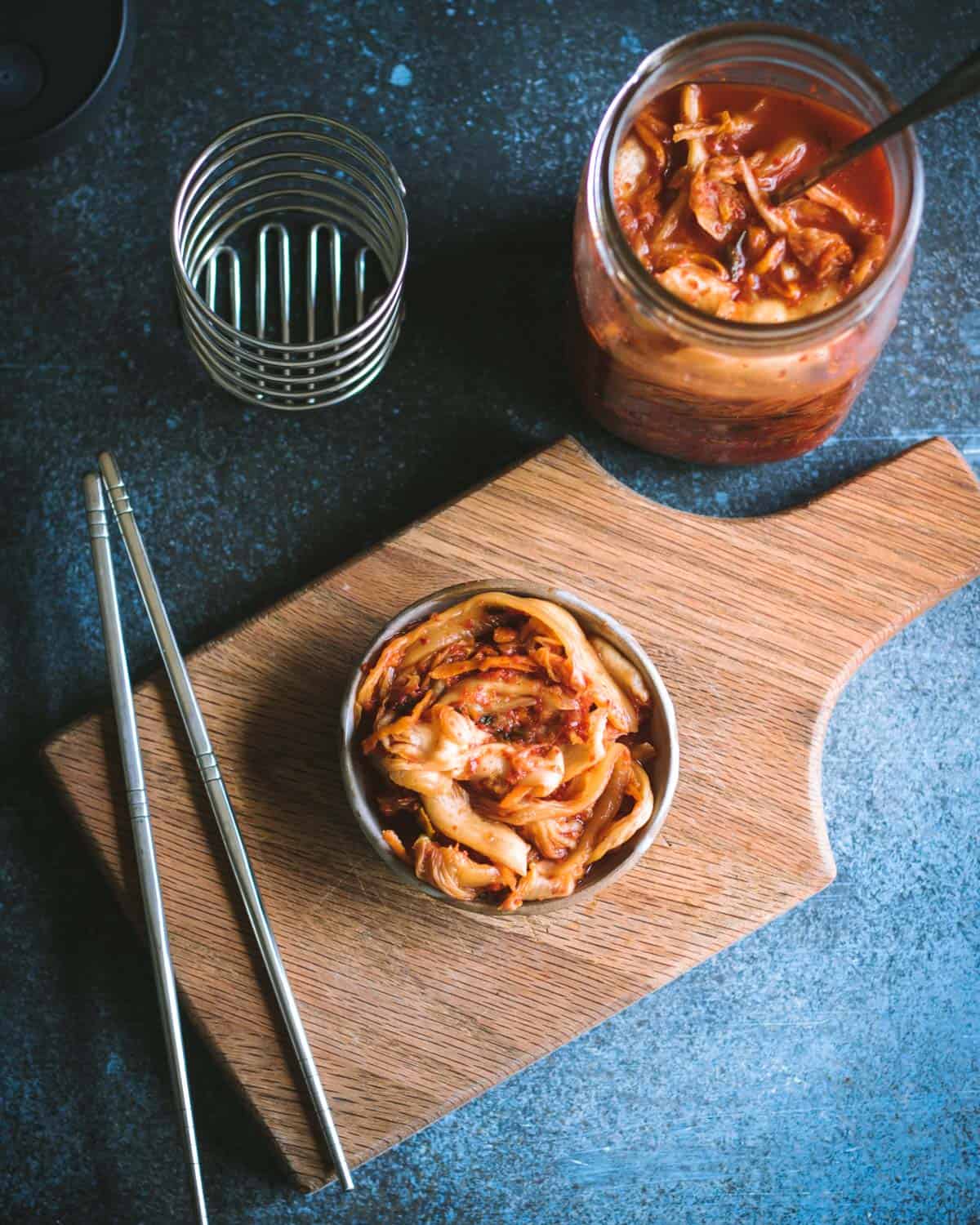 a bowl of kimchi with chopsticks