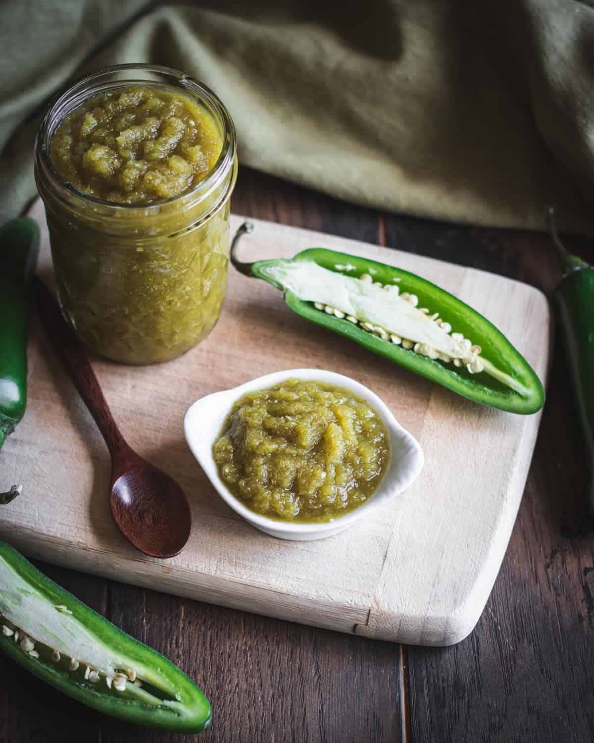 Fermented jalapeno hot sauce in a jar with a small bowl sitting out. 