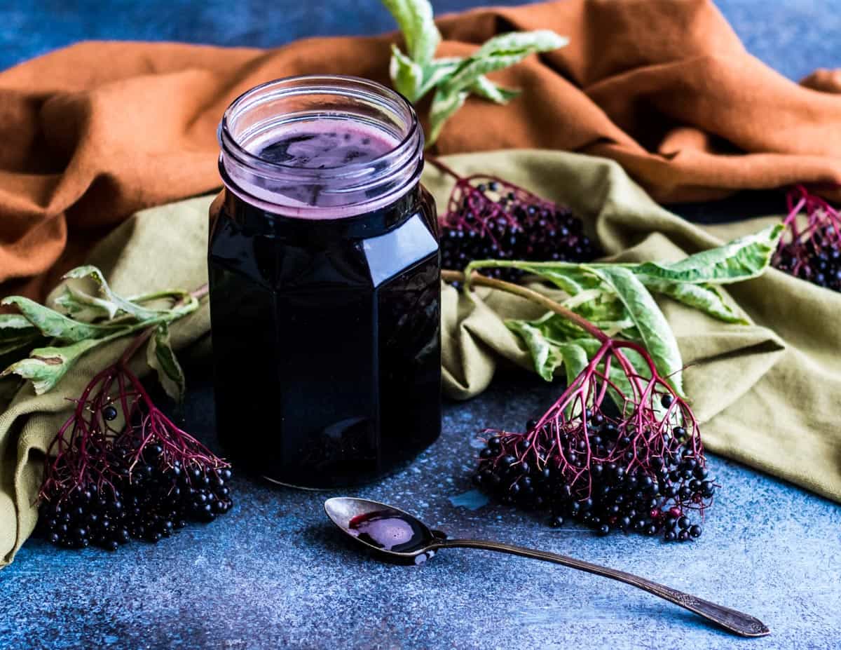 an open jar of elderberry syrup with a spoon