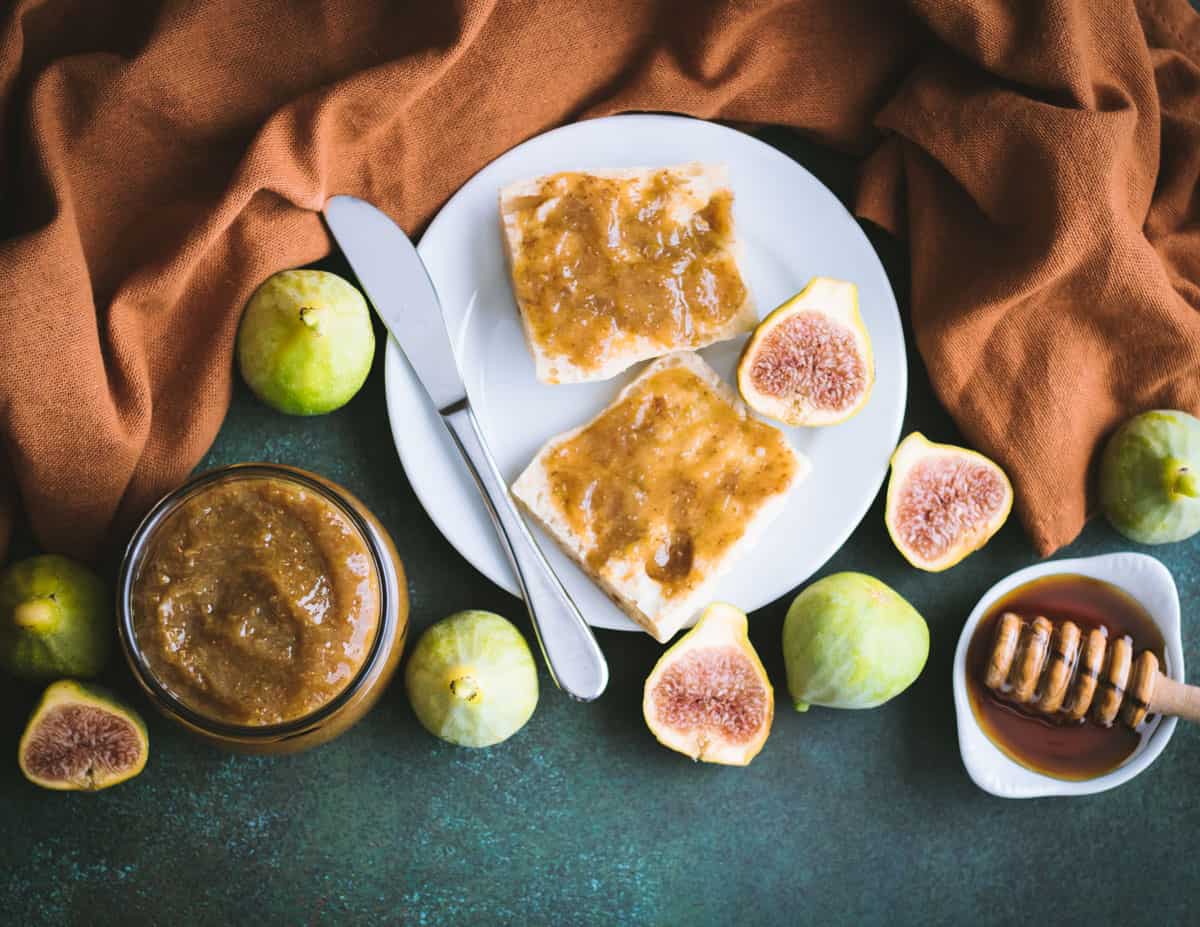 a jar of fig honey butter next to a plate of bread