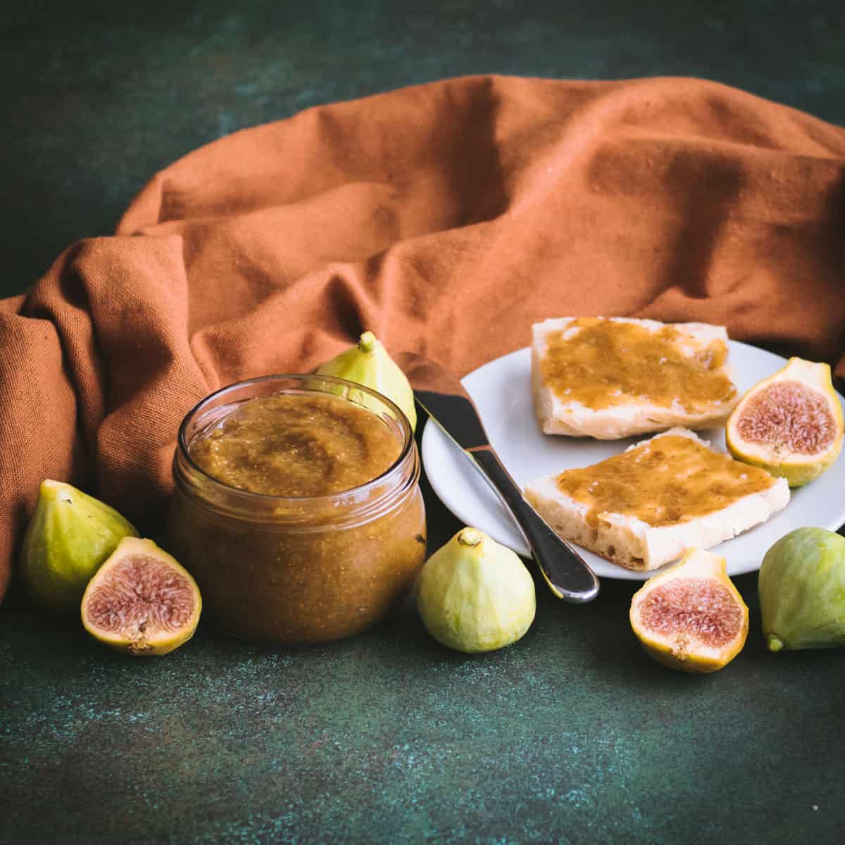 a jar of fig butter with figs on a table