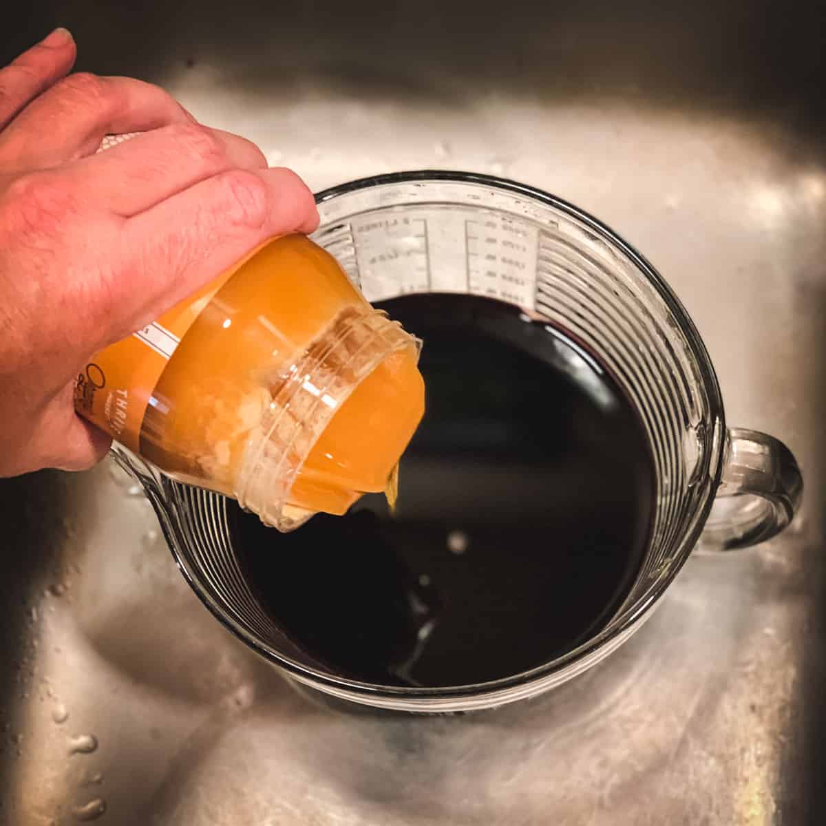 pouring honey to make elderberry syrup