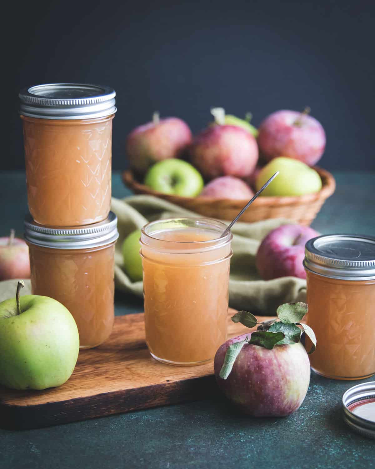 apple jelly with a spoon and a stack of two jelly jars