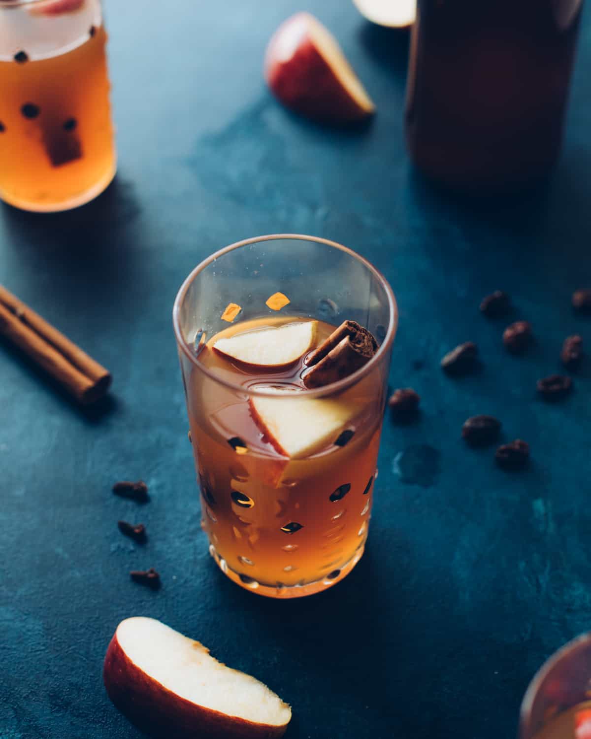 a glass of hard cider on a table with a cinnamon stick