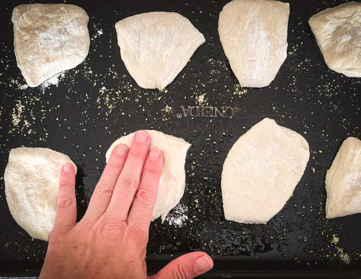 stretching the mini sourdough pizza dough on a sheet pan