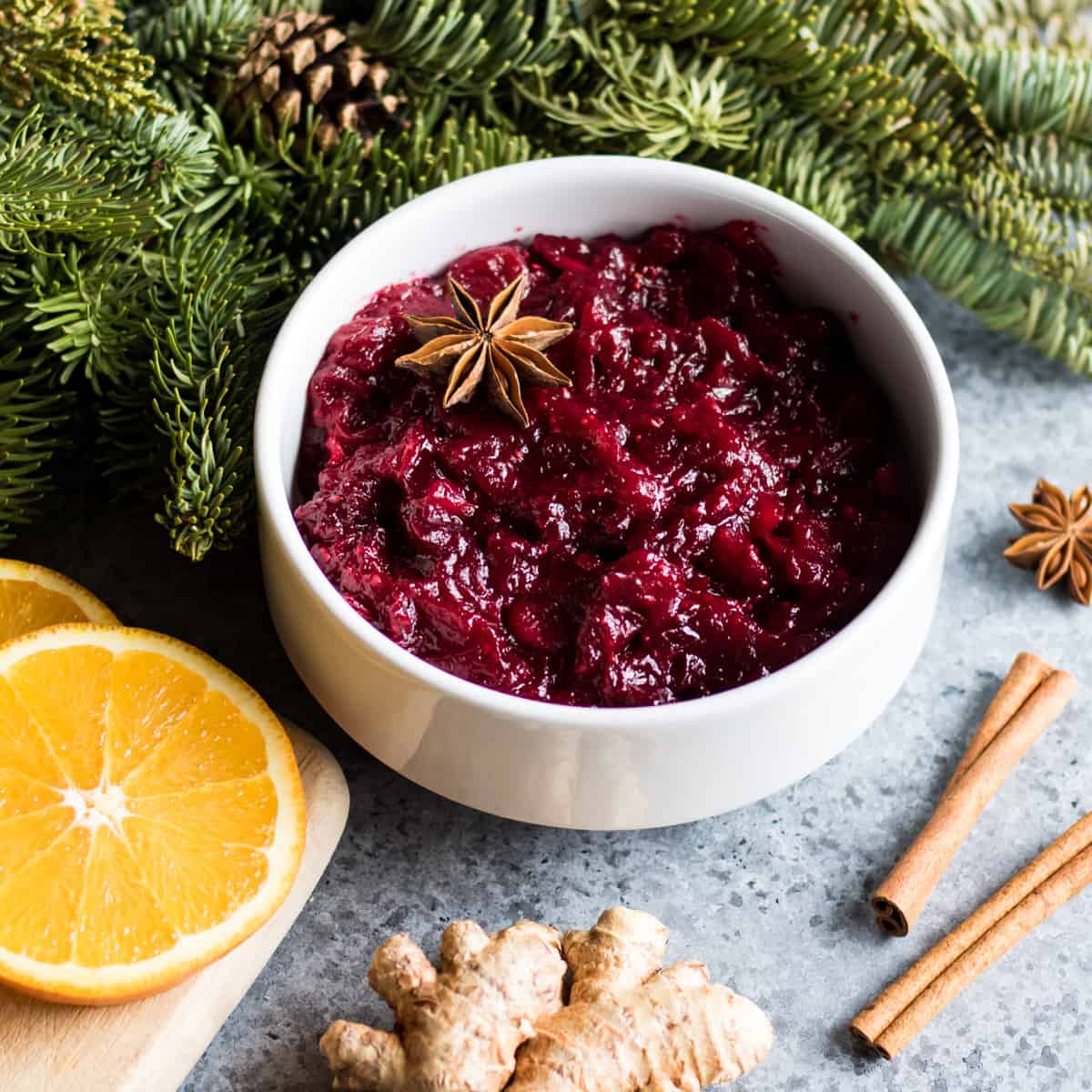 a bowl of spiced cranberry sauce with star anice, cinnamon, ginger and orange slices