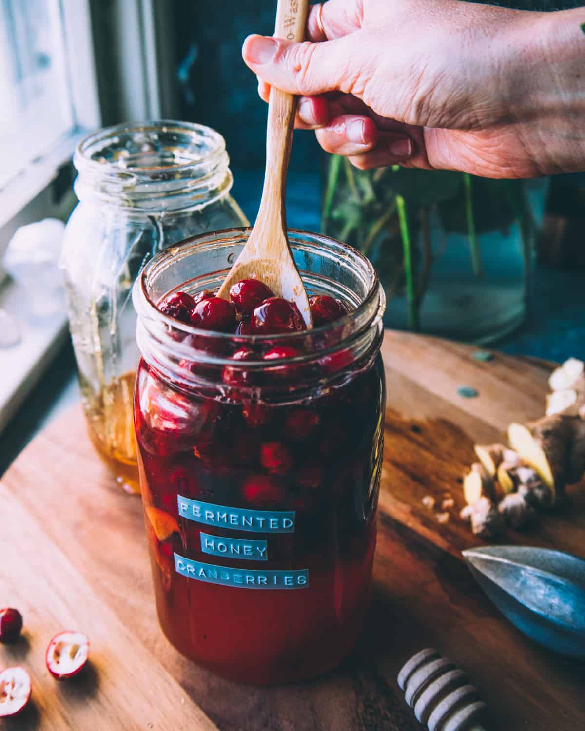 fermented honey cranberries in a jar with a wooden spoon