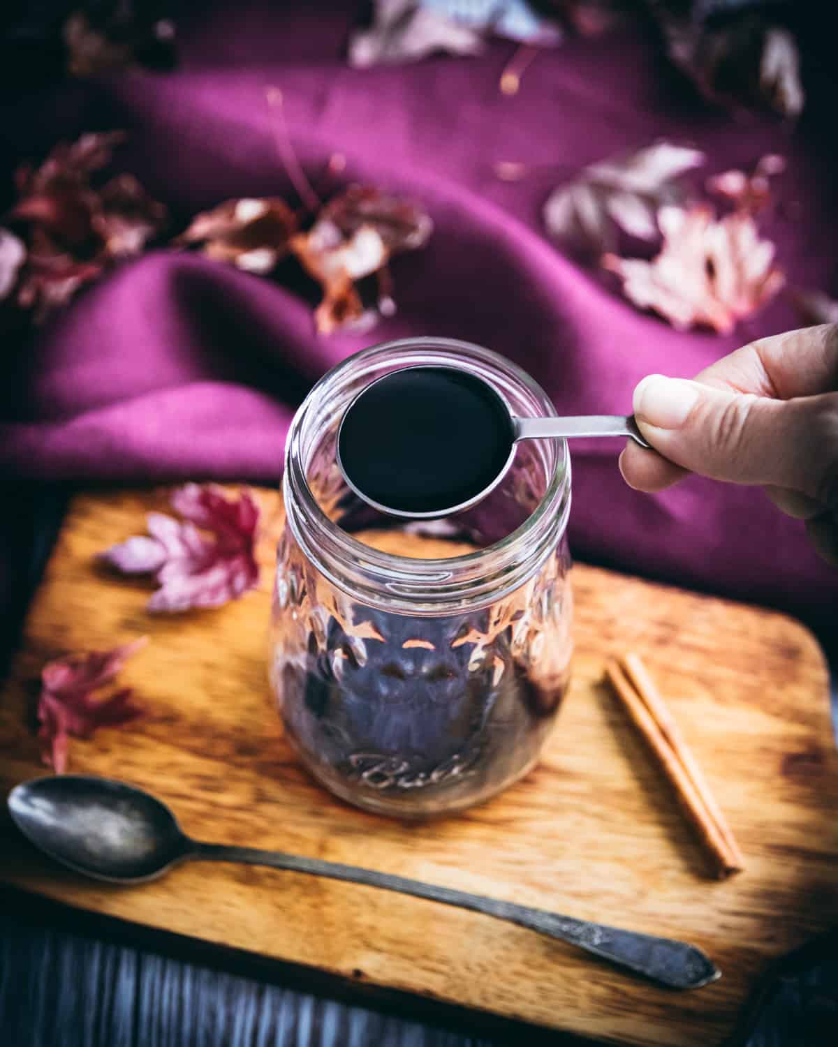 a hand holding a spoonful of elderberry syrup