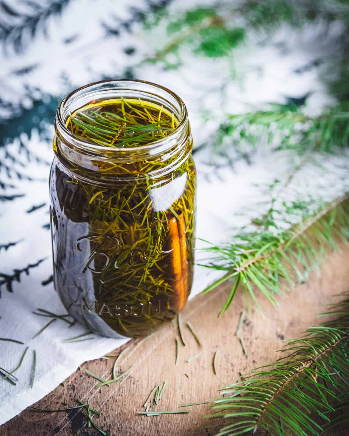 an open jar of conifer needles infusing in oil