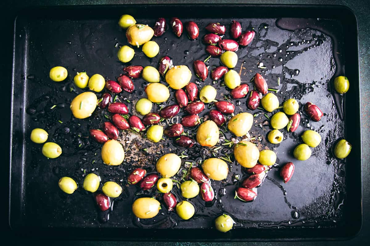 a variety of olives spread out on a baking sheet
