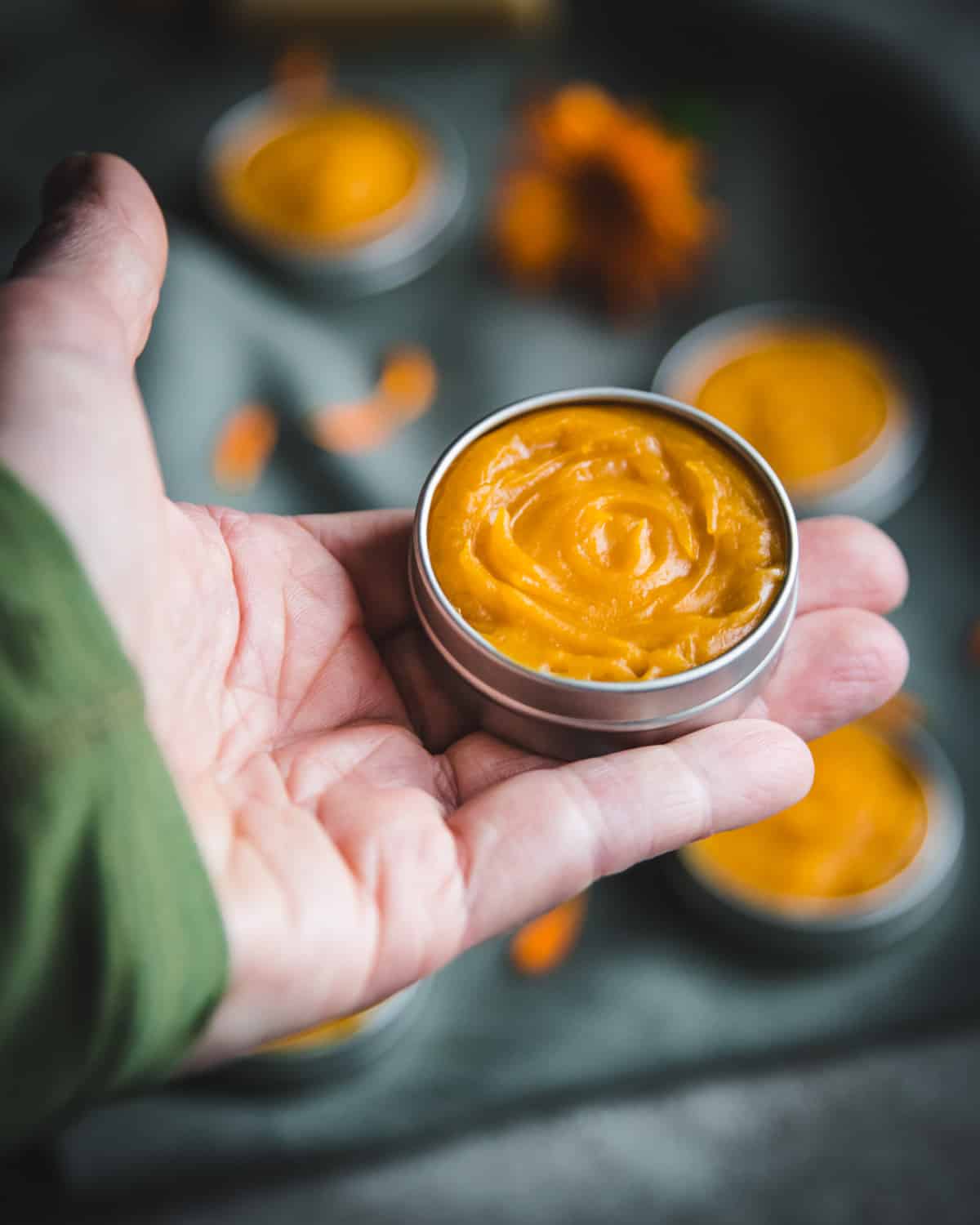 a hand holding a tin of manuka honey salve with propolis