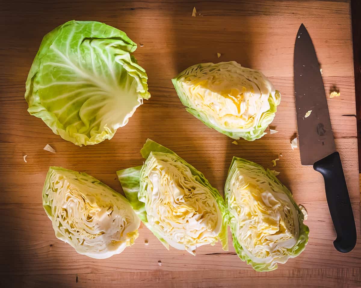 a cutting board with cabbage quarters and a cabbage leaf