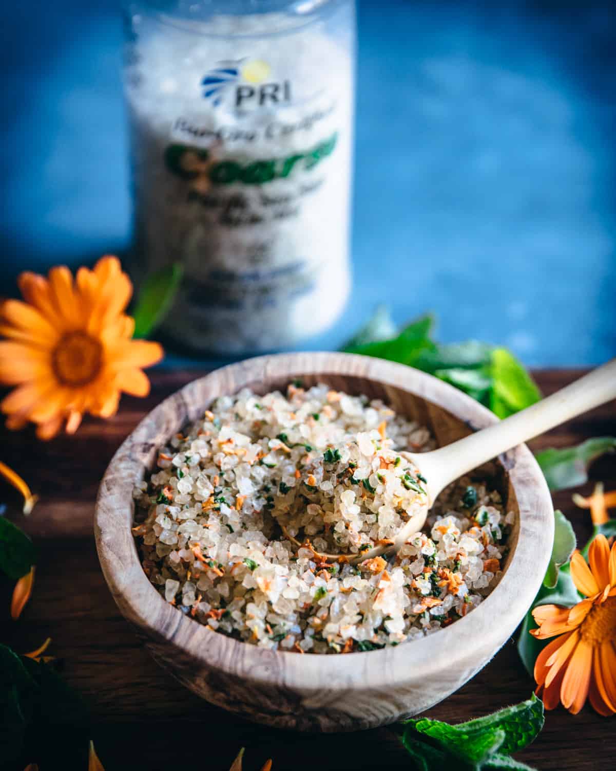 a wooden bowl of calendula mint bath salt and a wooden spoon