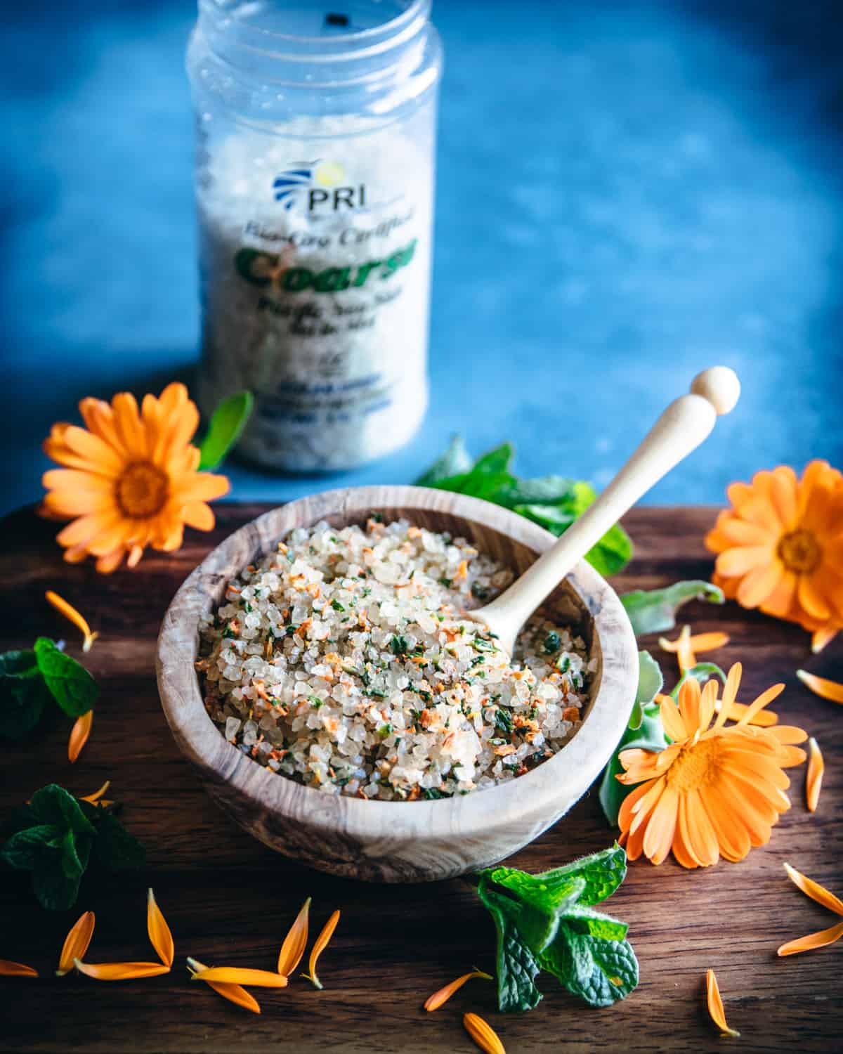 a wooden bowl of herbal bath salt with a spoon